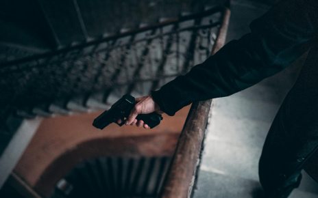 person in black jacket holding black gun